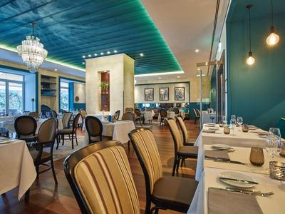 Elegant restaurant with set tables and comfortable striped chairs under a blue ceiling.