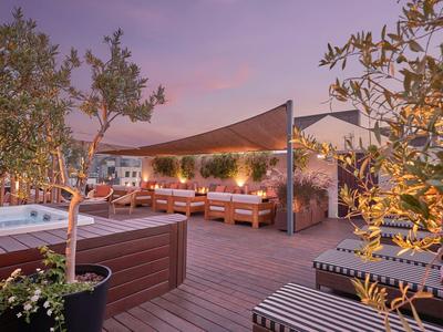 Cozy rooftop terrace with seating, plants, and illuminated hot tub at dusk