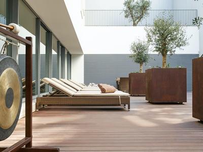 Modern outdoor area with lounge chairs, large plant pots, and wooden decking.