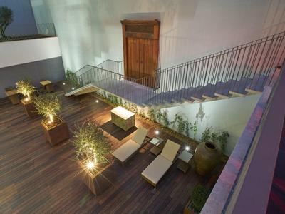 Modern hotel terrace outdoor area with wooden deck, sun loungers, and plants at dusk.