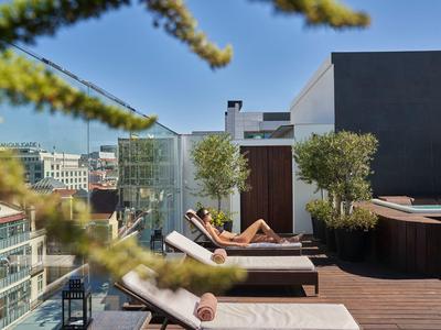 Rooftop terrace with lounge chairs, plants, and city views under clear sky