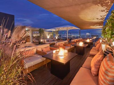 Accogliente terrazza sul tetto con aree salotto e luci di candela al crepuscolo.