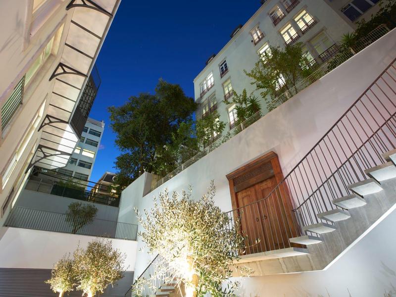 Night view of a lit courtyard with stairs and plants in a hotel.