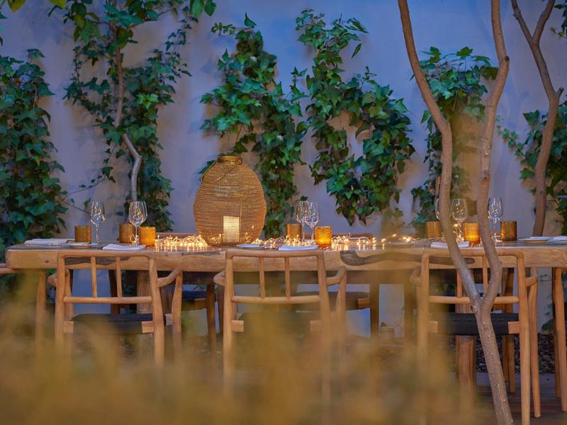 Cozy outdoor area with wooden tables, chairs, and candle lighting at dusk.