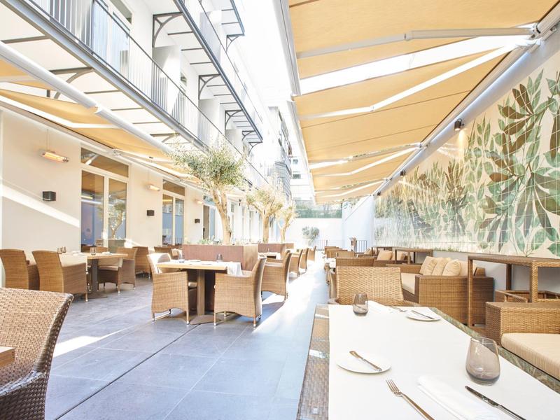 Bright terrace lounge with seating, sunshades, and tropical wall art.