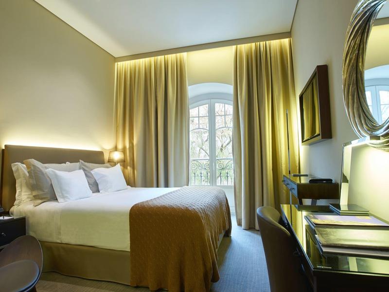 Cozy hotel room with large bed, desk, and decorative oval mirror.