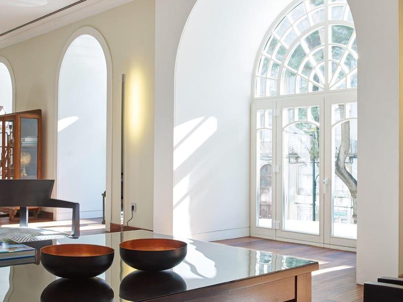 Bright hotel interior with large arches and modern furniture in neutral colors.