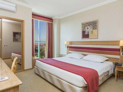 Habitación de hotel con cama doble, escritorio, silla y balcón con vista al mar.