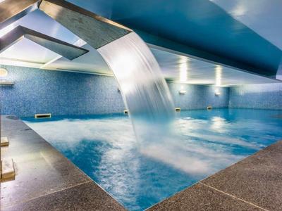 Piscina interior moderna con fuente y luz azul.