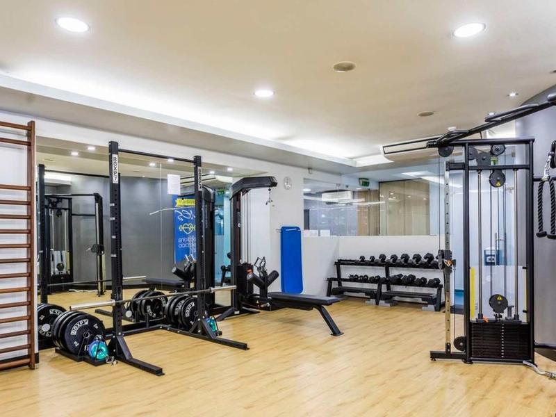 Gimnasio moderno con equipos, pesas y piso de madera en un hotel.