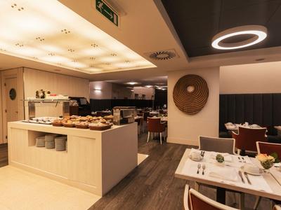 Modern dining area with buffet and set tables under warm lighting.