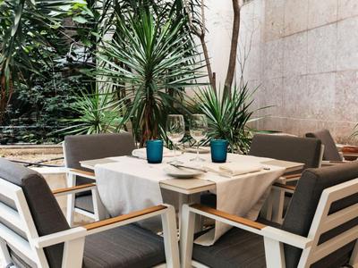 Cozy seating area with table, plants, and blue vases on a hotel terrace.