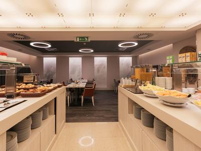 Buffet area with various breakfast foods and modern lighting in a hotel.