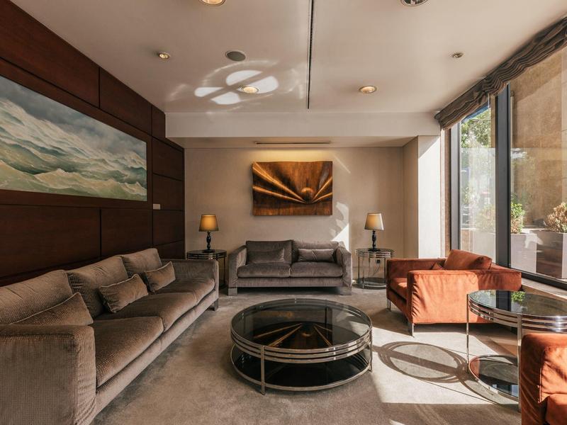 Cozy hotel lounge area with sofas, armchairs, and large window.