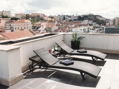 Deux chaises longues noires sur une terrasse sur le toit avec vue sur la ville.