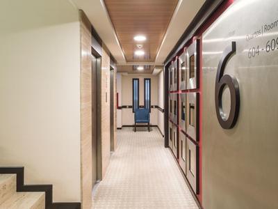 Corridoio d'hotel luminoso con ascensore e grandi numeri delle camere sulla parete.