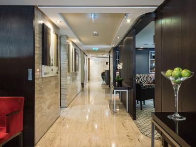 Corridoio d'hotel moderno con pavimento in marmo, specchi eleganti e illuminazione decorativa.