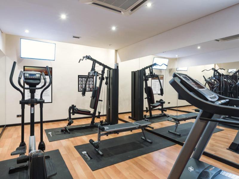 Palestra moderna con vari attrezzi su pavimento in legno e parete a specchio.