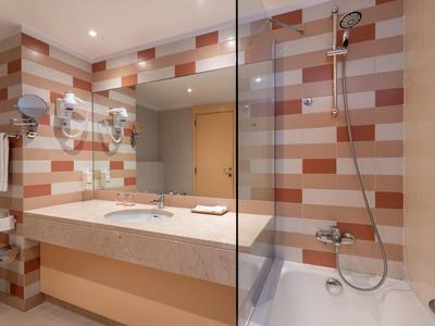 Bagno moderno con piastrelle colorate, ampia vasca e doppio lavabo.