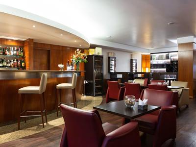 Bar moderna con poltrone in pelle e bancone in legno con luce calda.