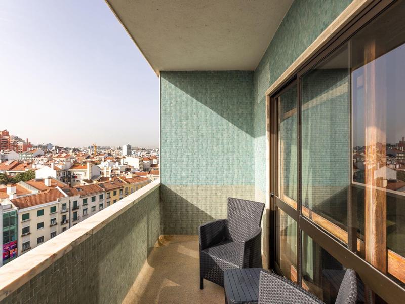 Balcone con sedie e vista sulla città con cielo sereno.