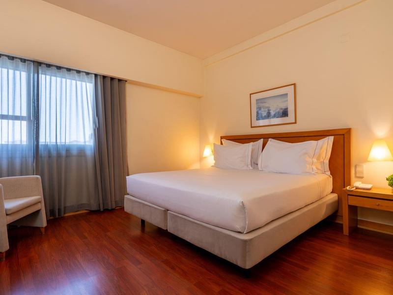 Camera d'albergo accogliente con letto matrimoniale, pavimento in legno e luce calda.