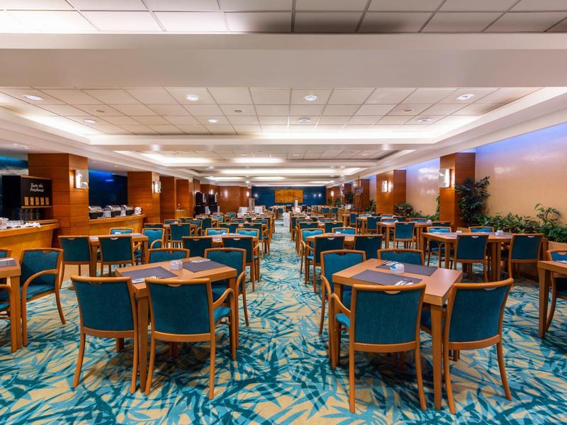 Ampia sala ristorante dell'hotel con sedie imbottite blu e moquette continua.
