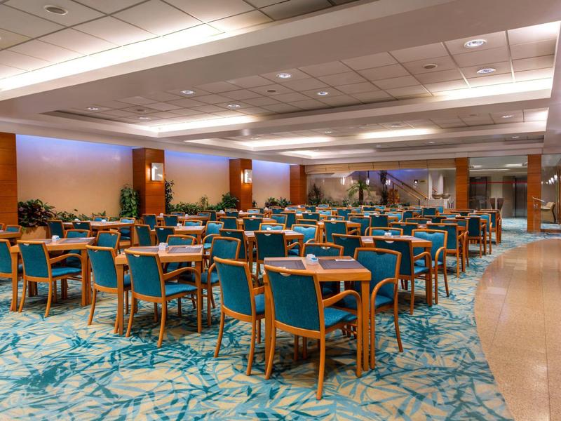 Ampia sala da pranzo moderna con sedie blu e luci a soffitto bianche.