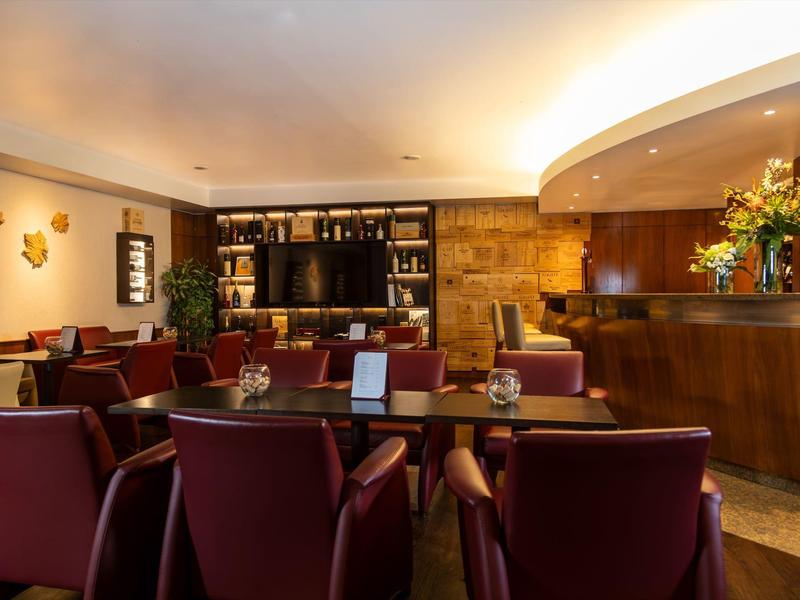 Interno accogliente di un bar in hotel con sedie bordeaux e bancone in legno