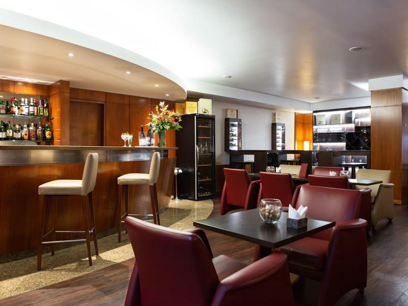 Bar moderna con poltrone in pelle e bancone in legno con luce calda.