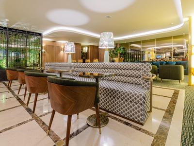 Lounge dell'hotel moderno con sedie imbottite e divani a motivo sotto una luce calda.