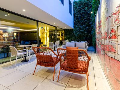 Accogliente area salotto esterna con sedie, tavolo e grande murale in un hotel moderno.