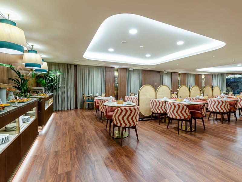 Ristorante moderno dell'hotel con pavimento in legno, sedie accoglienti e tavoli elegantemente apparecchiati