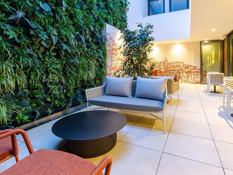 Terrazza accogliente con zona salotto moderna e parete verde al tramonto.