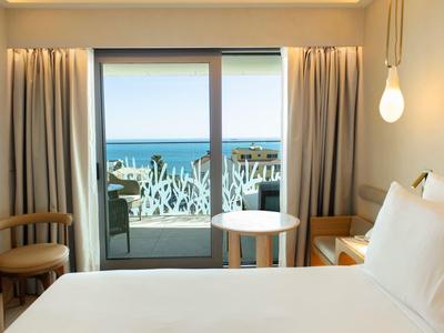 Nowoczesny pokój hotelowy z widokiem na morze i balkonem z dekoracyjną balustradą.