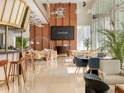 Jasna, nowoczesna restauracja hotelowa z barem, wygodnymi miejscami do siedzenia i dużymi oknami.