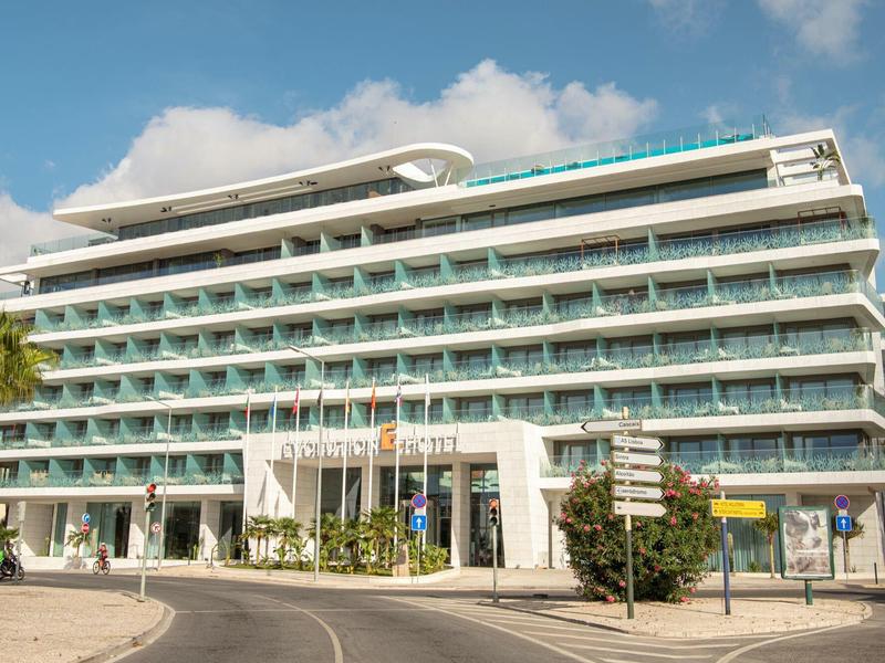 Nowoczesny hotel z wieloma piętrami i balkonami pod niebieskim niebem.