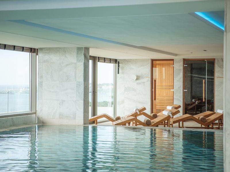 Basen wewnętrzny z leżakami i dużym oknem z widokiem na morze