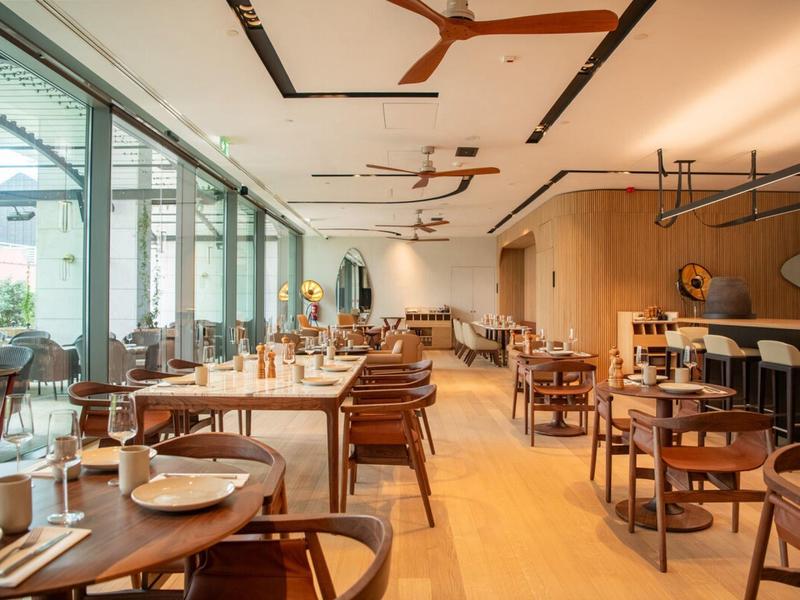 Jasna, nowoczesna restauracja z drewnianymi meblami i dużymi oknami wpuszczającymi światło dnia.