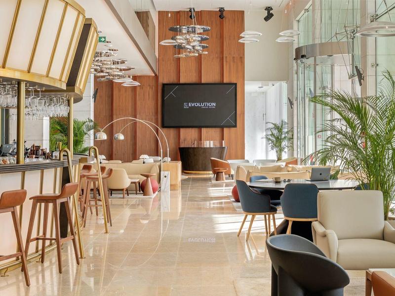 Jasna, nowoczesna restauracja hotelowa z barem, wygodnymi miejscami do siedzenia i dużymi oknami.