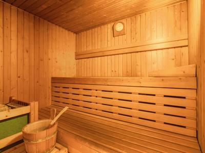 Holzsauna mit Holzbänken, Eimer und Schöpfkelle, warme Beleuchtung.