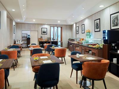 Moderner Hotelfrühstücksraum mit bestückten Tischen und gemütlichen Stühlen in warmen Farben.