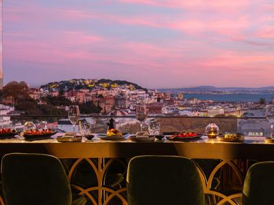 Vista su una città con colline al tramonto da un ristorante dell'hotel con tavolo apparecchiato.
