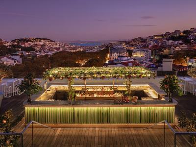 Terrazza panoramica illuminata con bar e posti a sedere in città al crepuscolo.
