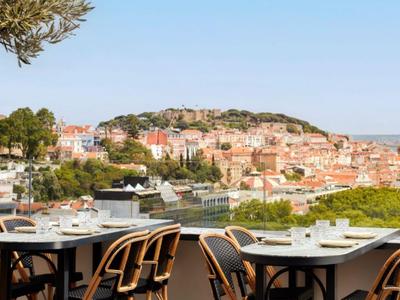 Terrazza con tavoli apparecchiati e vista sul mare in una città costiera in una giornata di sole.