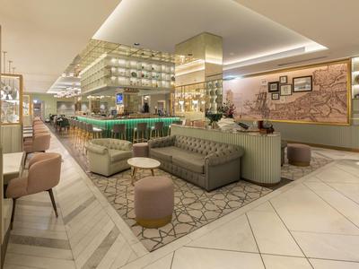 Lounge d'hotel moderna con sedute eleganti, bar e luci calde.