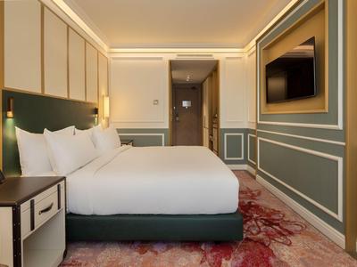 Camera d'hotel spaziosa con letto grande, tappeto elegante e TV moderna.