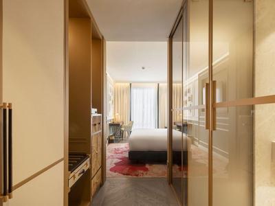 Vista di una camera d'hotel moderna con letto grande, balcone e mobili in legno chiaro.