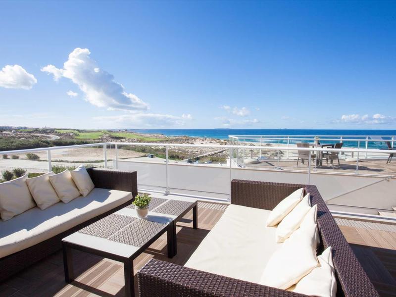 Terrazza moderna con divani comodi e vista sul mare sotto un cielo azzurro.