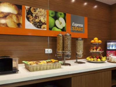 Ontbijtbuffet met muesli, vers fruit en dranken in een moderne hotelkamer.